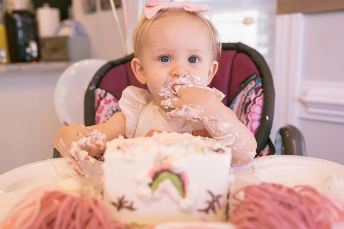 A one-year-old covered in cake at their first birthday party
